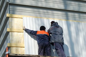 Рабочие крепят профлист на стену